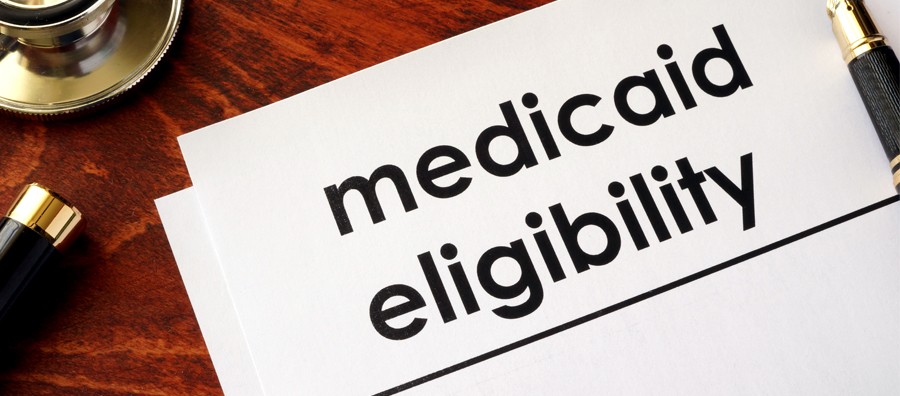Medicaid eligibility document on a wooden desk with a pen and stethoscope