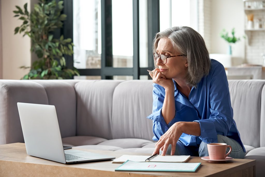 Senior mature older woman watching business training, online webinar on laptop computer remote working or social distance learning from home.