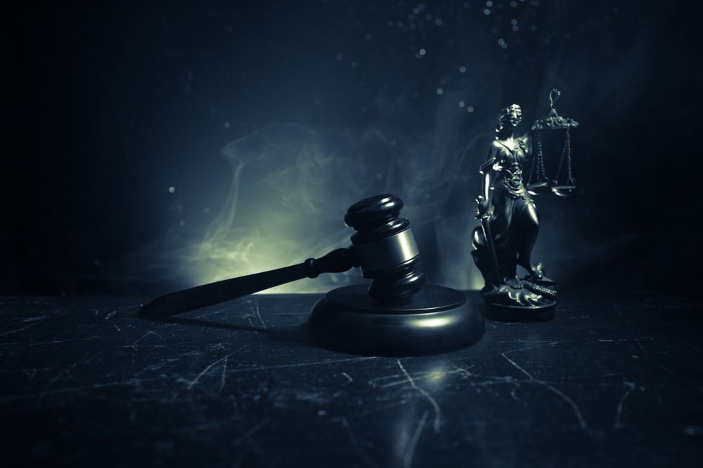 Gavel and Lady Justice statue in dramatic dark setting