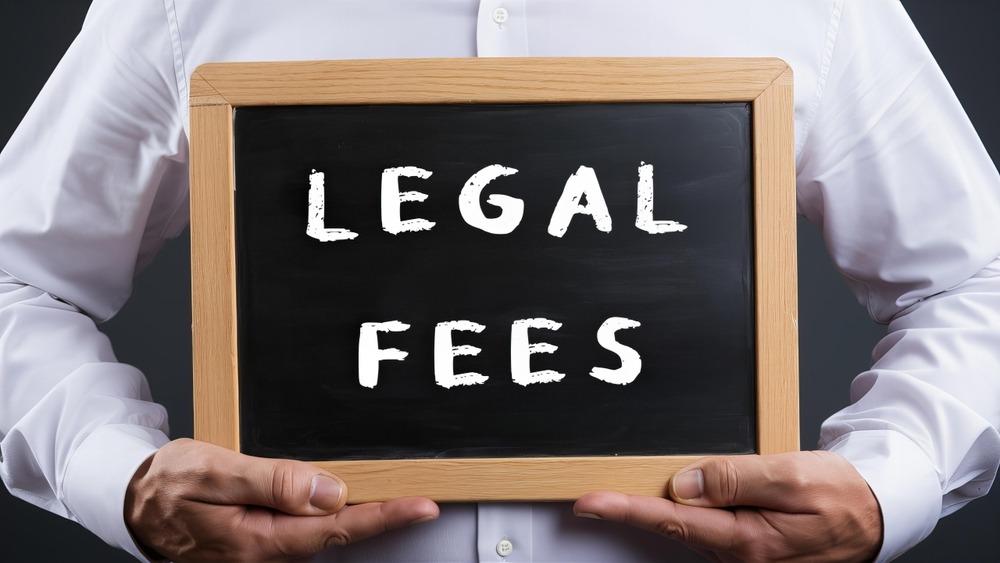 Person holding chalkboard sign with words "Legal Fees"