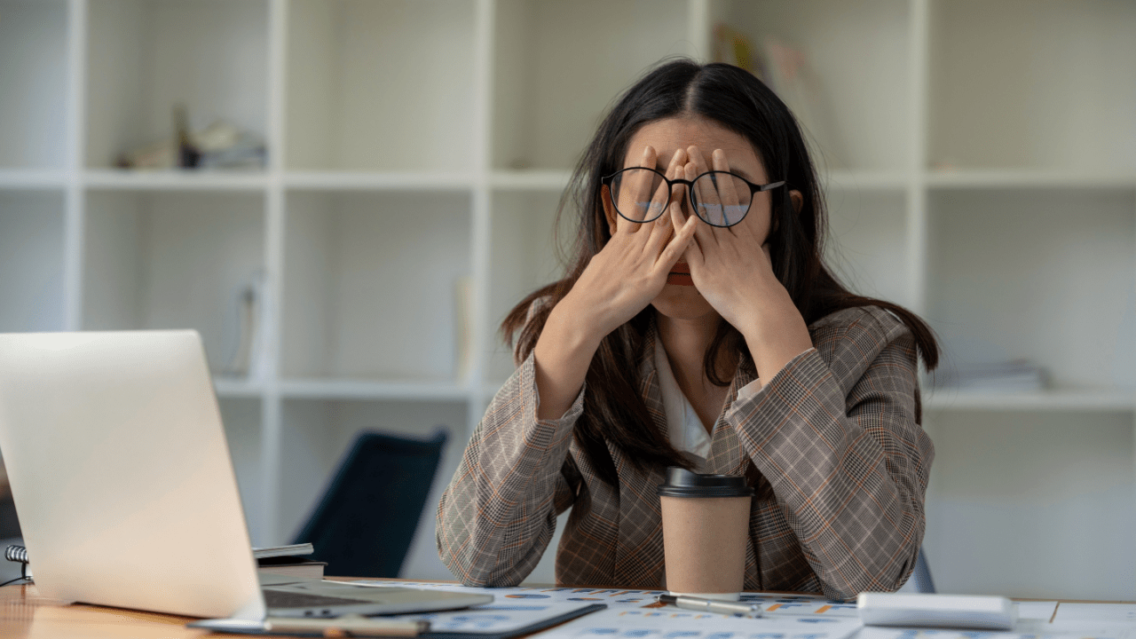 Can you get SSDI for depression Stressed businesswoman rubbing her eyes while working at desk with laptop and paperwork in modern office