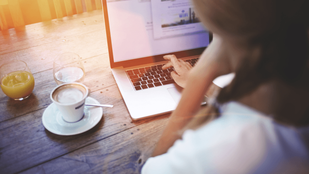 Woman at café reviewing SSDI back pay vs. retroactive pay on laptop
