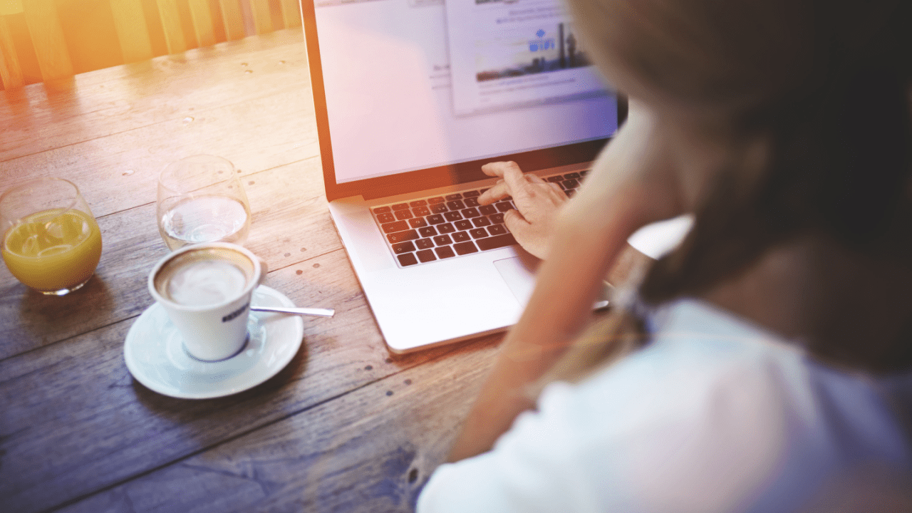 Woman at café reviewing SSDI back pay vs. retroactive pay on laptop