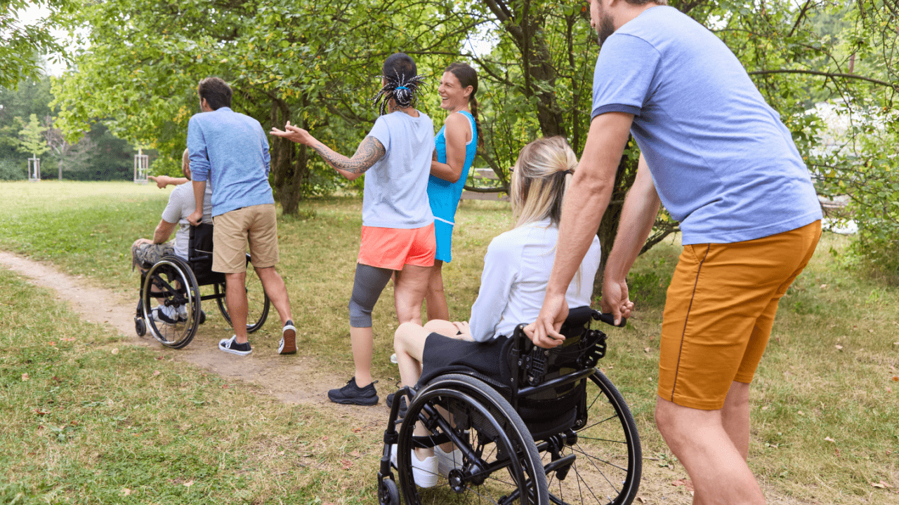 Group of people including wheelchair users participating in outdoor recreational activity in a park setting