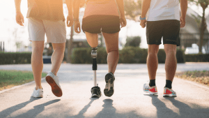 Three people jogging together on a path, with the middle runner using a running prosthetic leg