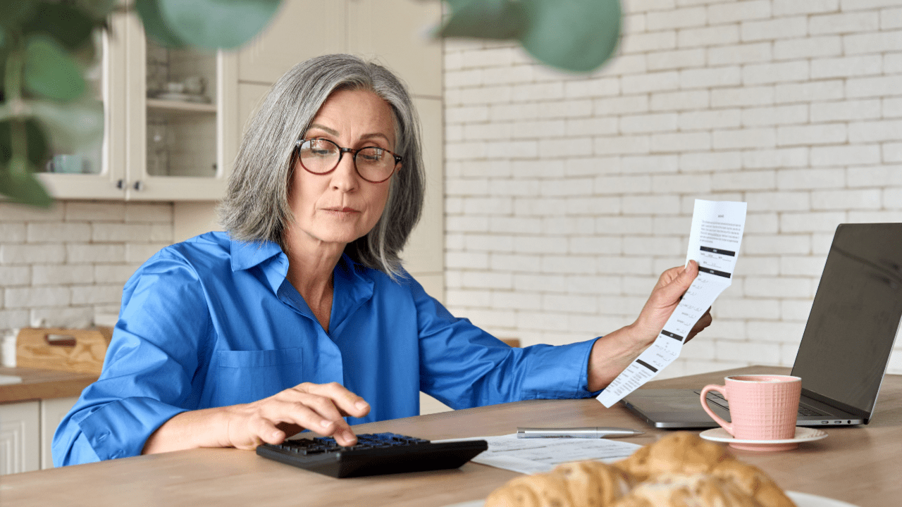 Senior woman calculating finances at home — at what age is it easier to get SSDI?