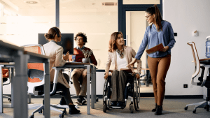 Professional woman in wheelchair collaborating with standing colleague in modern inclusive office workspace