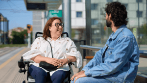 Woman in wheelchair having friendly conversation with man at public transit station
