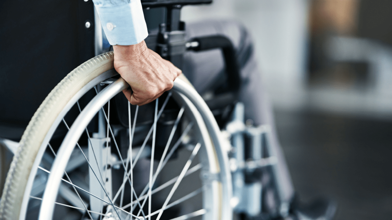 Close-up of hand gripping wheelchair wheel rim showing mobility and independence in professional setting