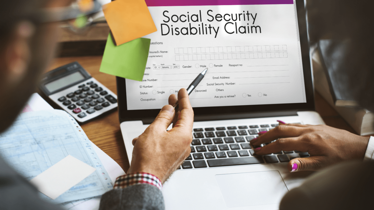 Person filling out Social Security Disability Claim form on laptop computer with calculator and paperwork on desk