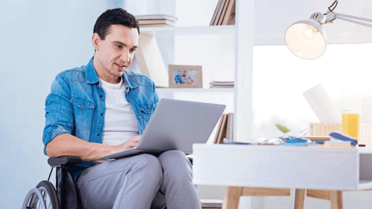 Man in wheelchair researching what is the best state to live in on disability using laptop