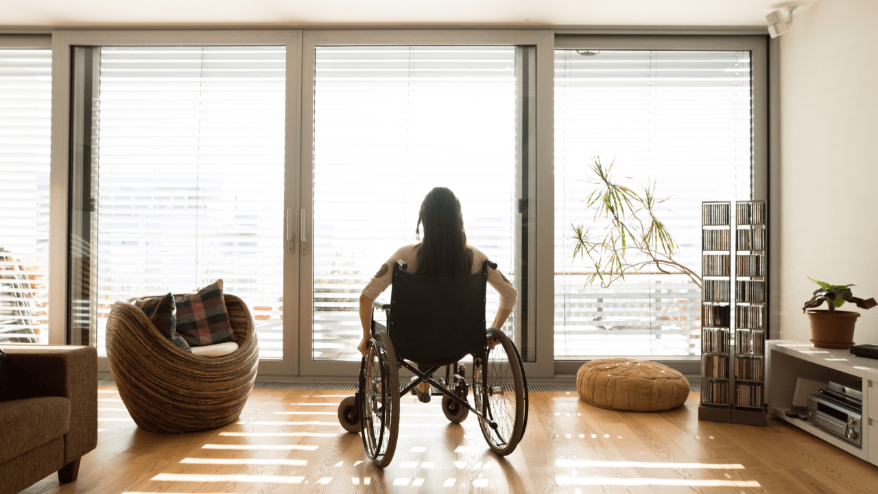 Person in wheelchair looking out window considering what is the best state to live in on social security disability