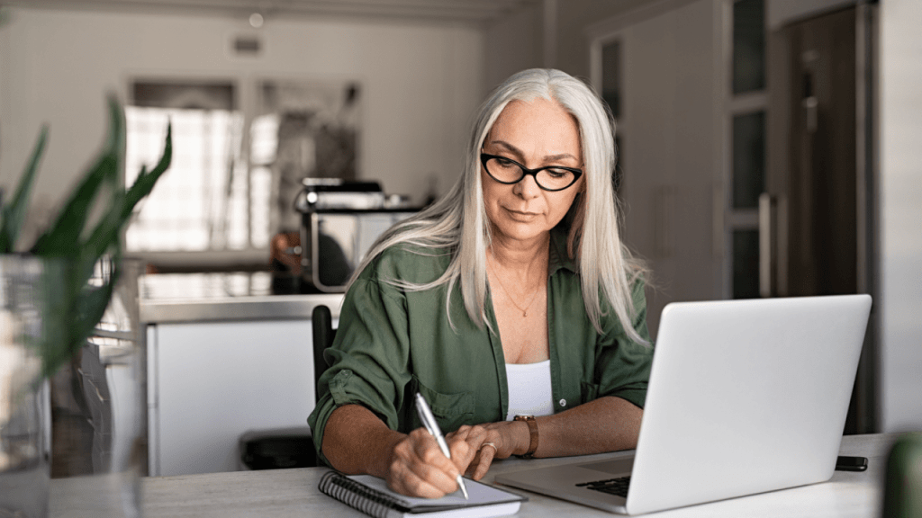 Woman researching SSDI vs SSI benefits differences on laptop while taking notes at home office desk