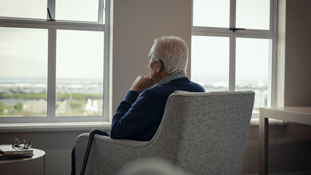 Senior man sitting by window thinking about what are the disadvantages of Social Security disability