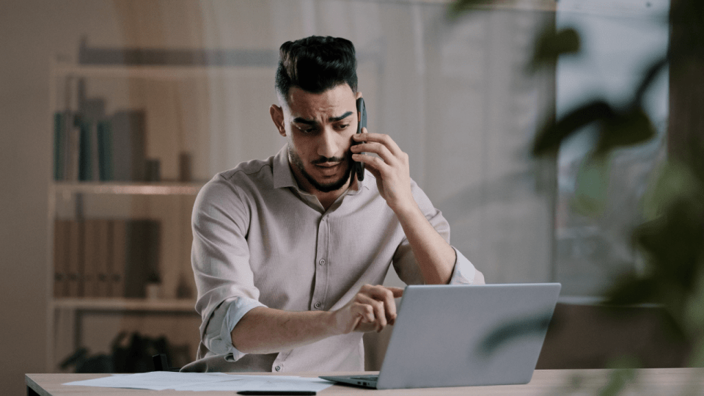 Man on phone call researching what is the most SSI disability will pay while using laptop