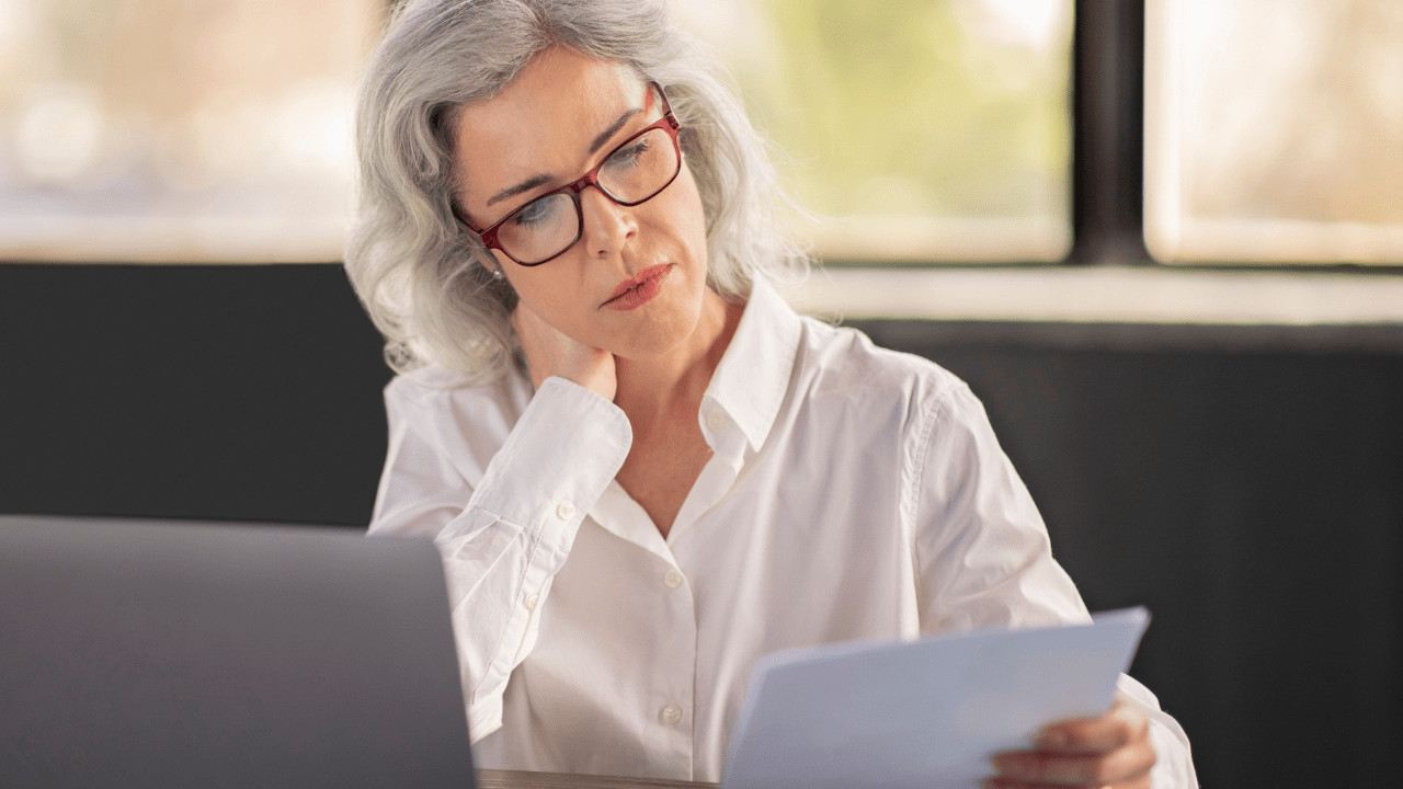 Senior woman with glasses reviewing documents to learn can you get $3,000 a month in Social Security