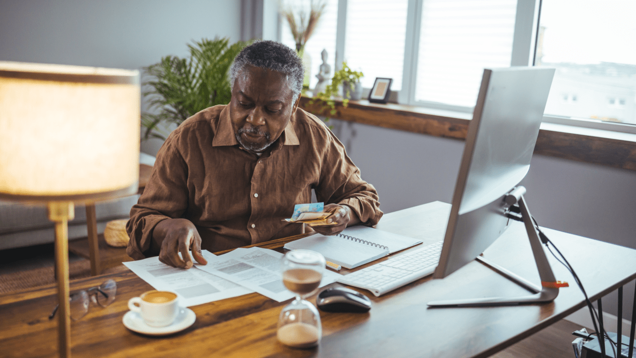 Senior man reviewing Medicare documents and costs while researching do I have to pay for Medicare on SSDI benefits
