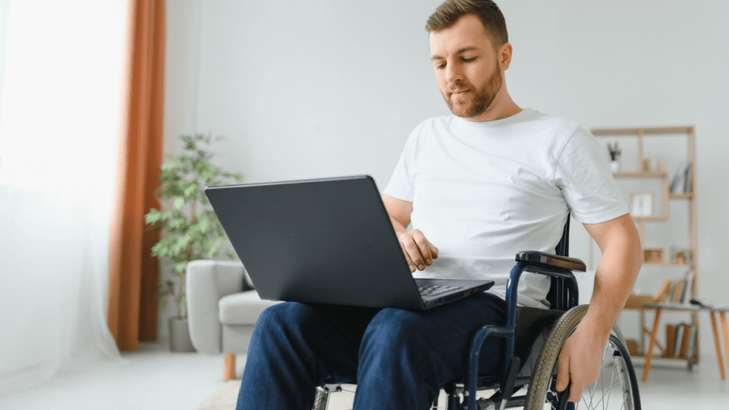 Man in wheelchair using laptop to research benefits - what is the minimum SSDI payment amount