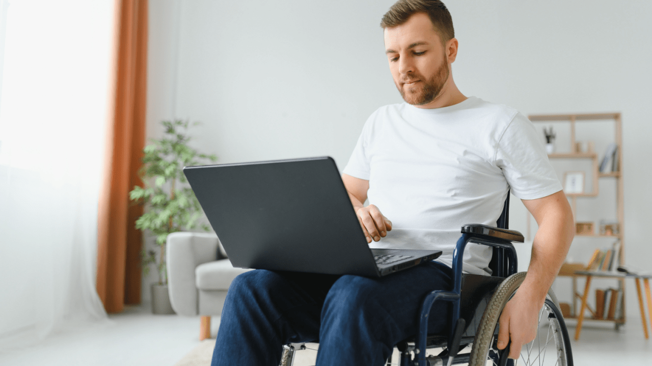 Man in wheelchair using laptop to research benefits - what is the minimum SSDI payment amount