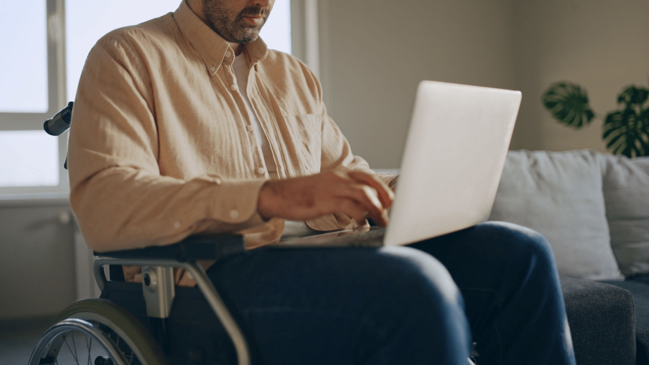 Man in wheelchair researching what illnesses automatically qualify for disability benefits on laptop computer