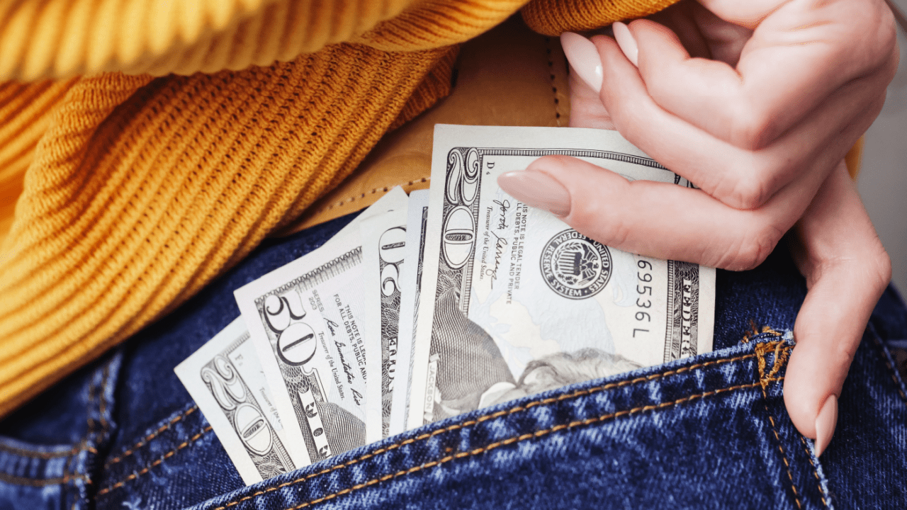 Person in yellow sweater protecting dollar bills in jeans pocket representing SSDI back pay after reconsideration approval timeline