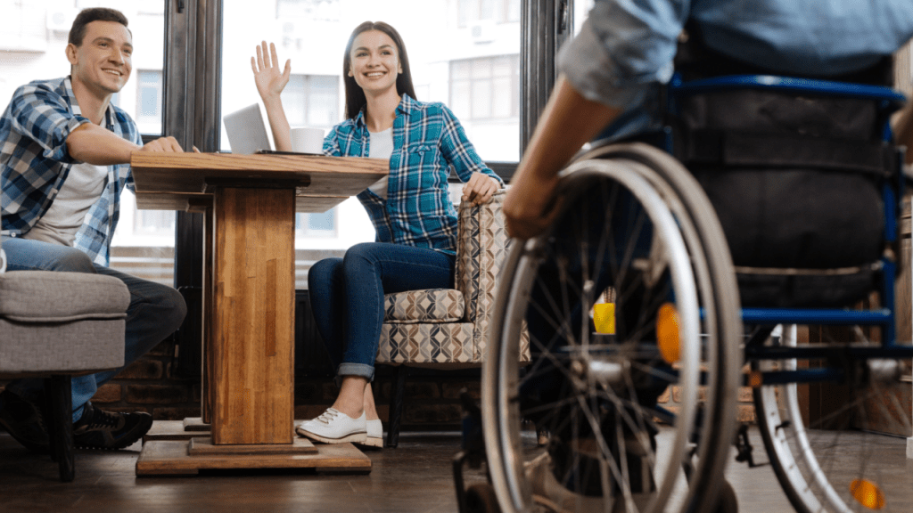 Person in wheelchair at café with friends discussing what are the four largest disability categories and inclusion