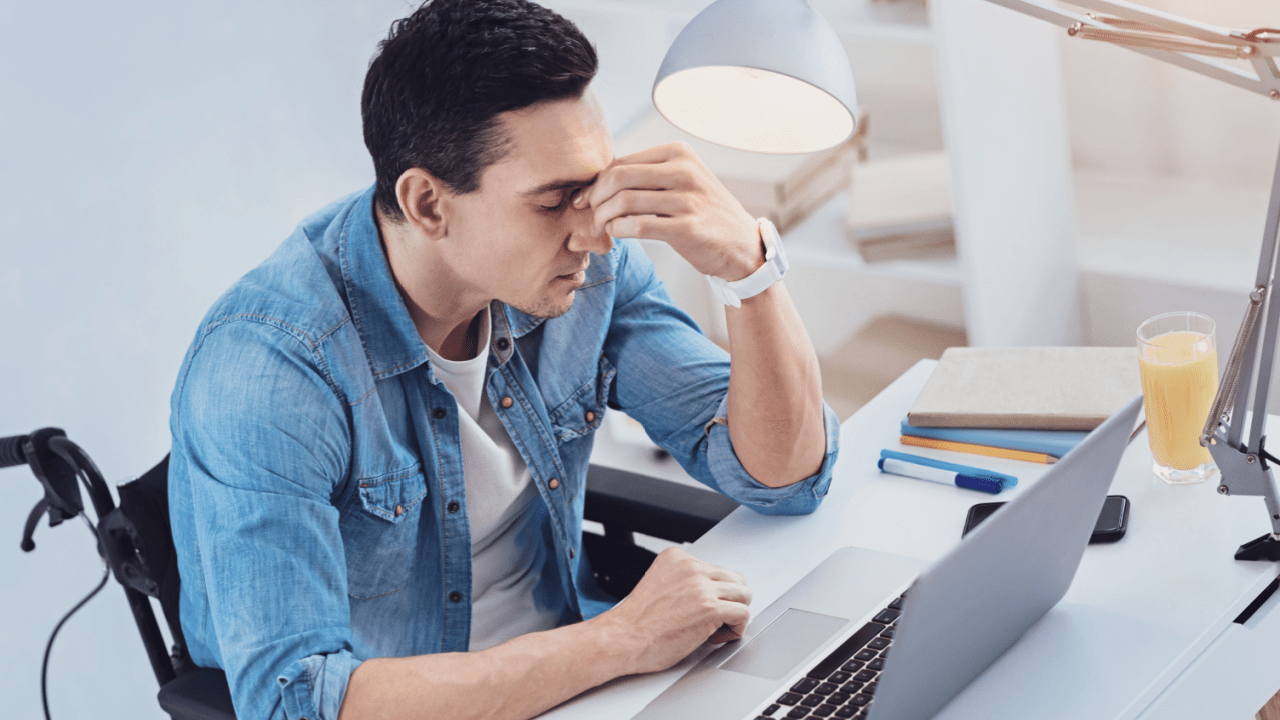 Stressed man reviewing SSDI denial paperwork wondering why do so many people get denied SSDI benefits
