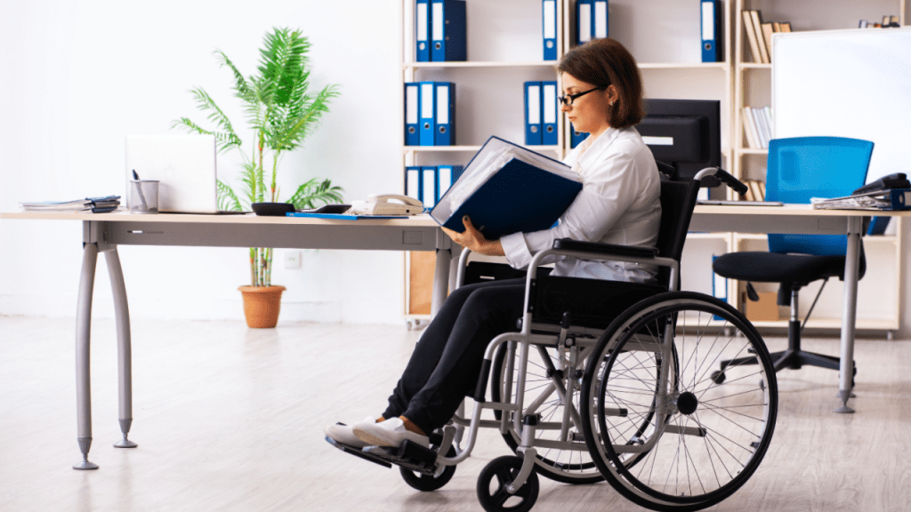 Professional woman in wheelchair reading documentation about what gives 100 disability rating in modern office setting