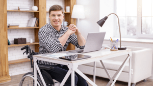 Young man in wheelchair researching what states pay the highest Social Security disability benefits on laptop computer