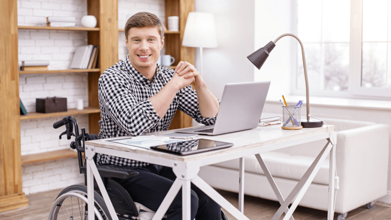 Young man in wheelchair researching what states pay the highest Social Security disability benefits on laptop computer