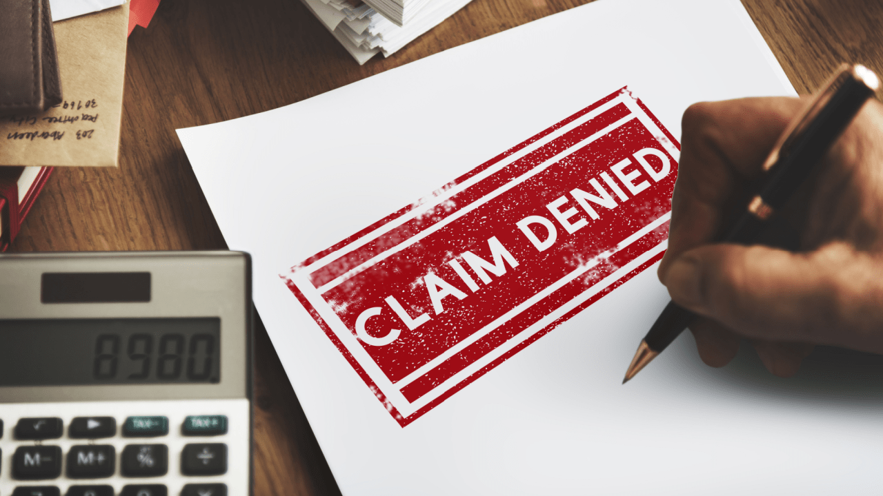 Red claim denied stamp on paper showing what happens after SSDI reconsideration is denied
