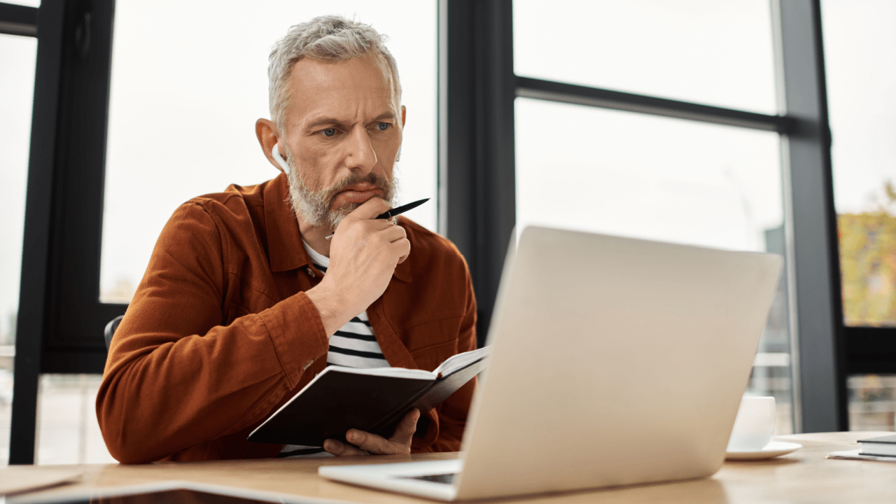 Man checking laptop and taking notes to learn how do I know if my SSDI is approved