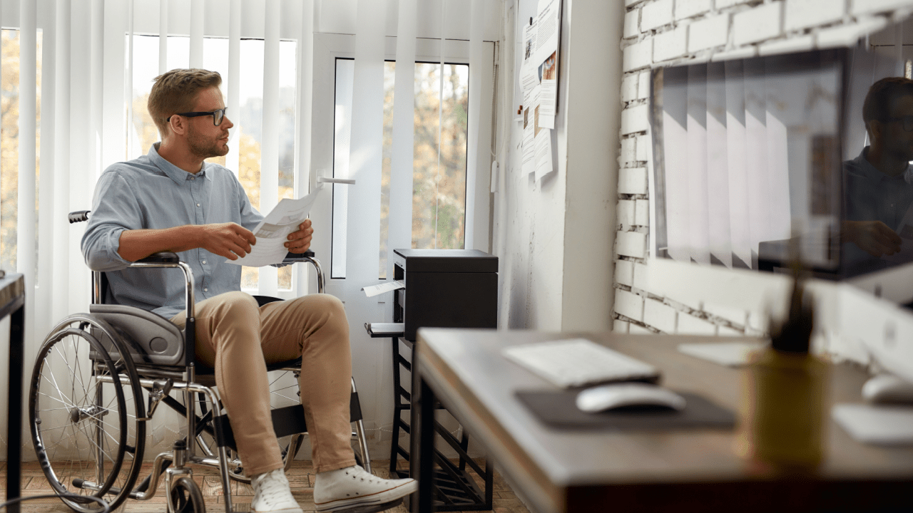 Man in wheelchair reviewing disability application documents wondering what disqualifies a person from disability benefits