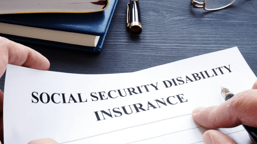 Social security disability insurance application document being held on professional desk with law books, pen, and glasses