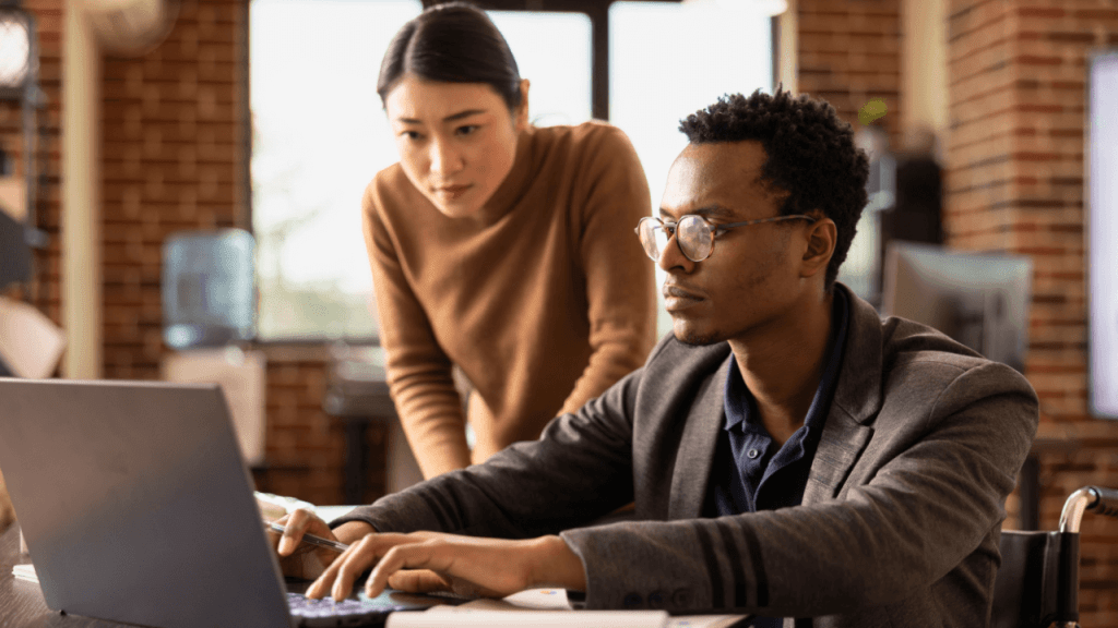 Two people reviewing SSDI CDR documents on a laptop in an office setting