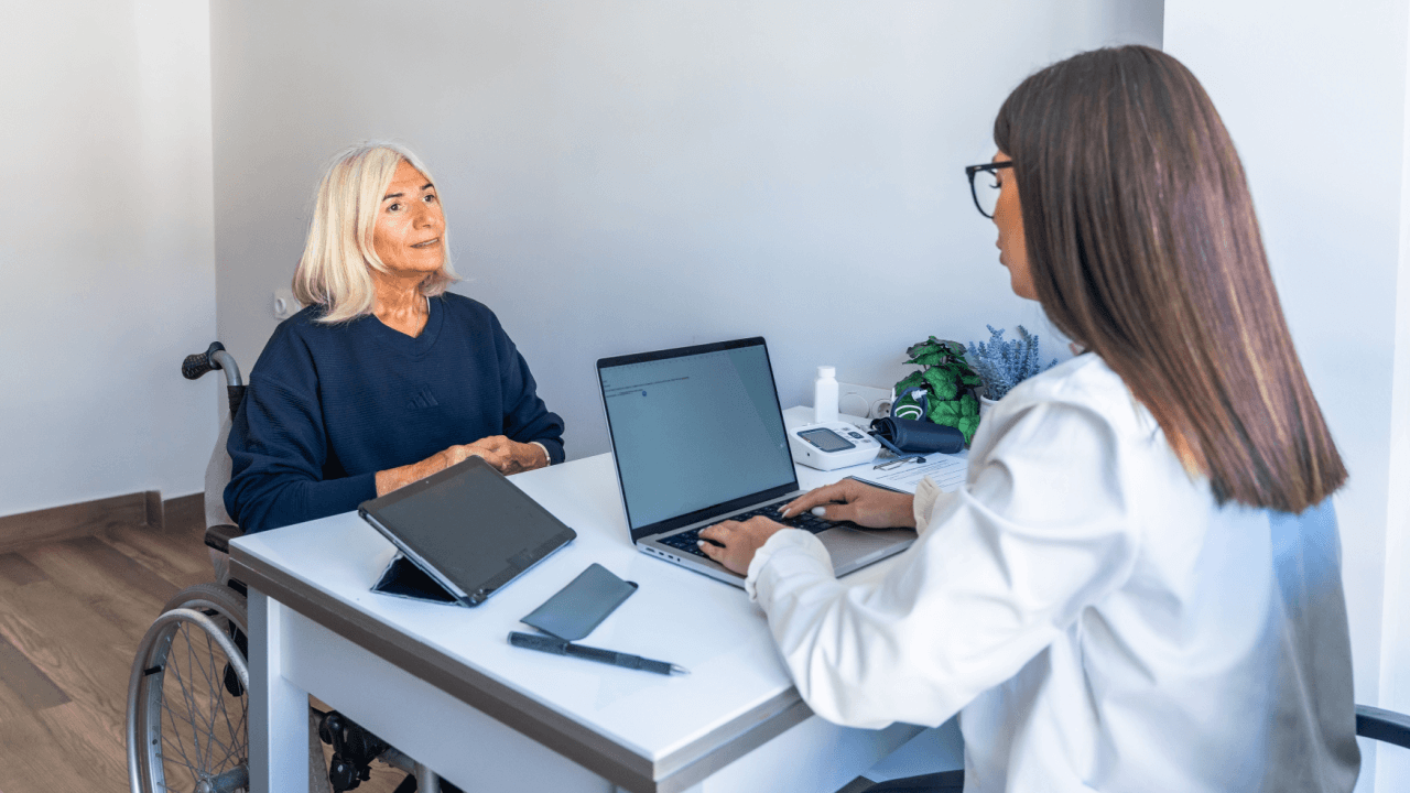Older woman in a wheelchair consulting with a healthcare professional about SSDI CDR reviews and disability benefits