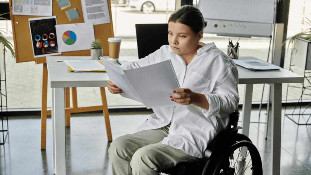 A woman in a wheelchair reviewing disability documents at her office desk while preparing for a continuing disability review