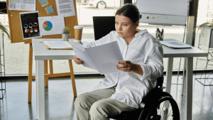 A woman in a wheelchair reviewing disability documents at her office desk while preparing for a continuing disability review