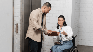 A man holding a clipboard reviews CDR documents with a woman in a wheelchair during an SSDI Continuing Disability Review consultation