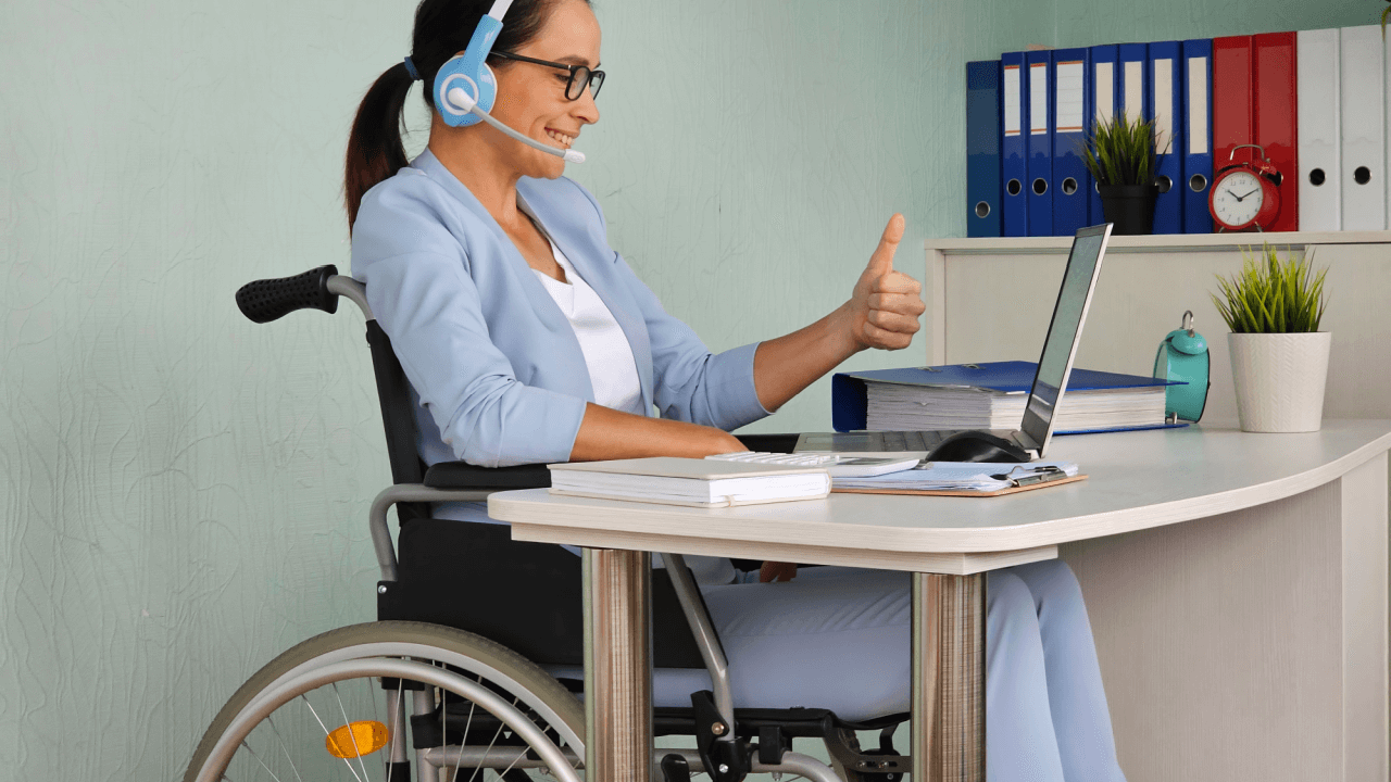 Woman in wheelchair with headset giving thumbs up while researching how long does it take to get a decision on SSDI after CDR on her laptop