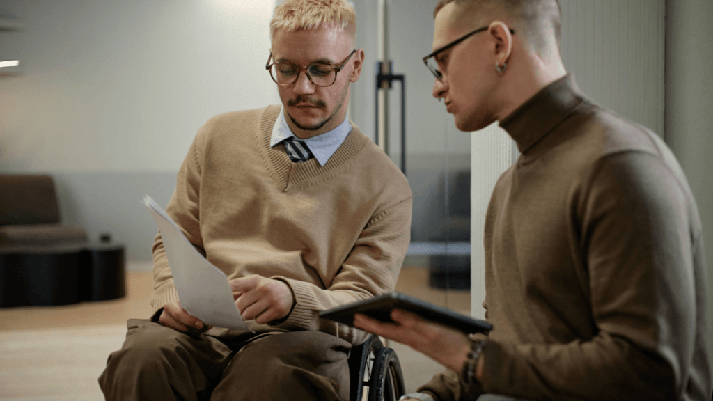 A person using a wheelchair reviews SSDI documents with an advisor, representing the process of understanding how long it takes to get a decision on SSDI after CE
