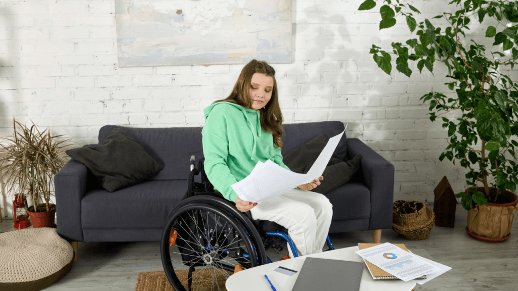 A young woman in a wheelchair reviewing Social Security disability documents at home, researching how long a Social Security disability check is good for
