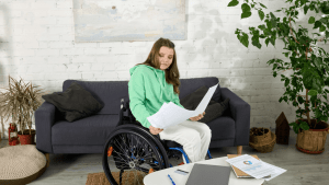 A young woman in a wheelchair reviewing Social Security disability documents at home, researching how long a Social Security disability check is good for