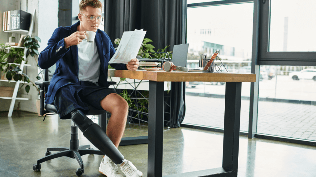 A man with a prosthetic leg sitting at a desk reviewing documents, representing someone researching is it hard to pass a continuing disability review