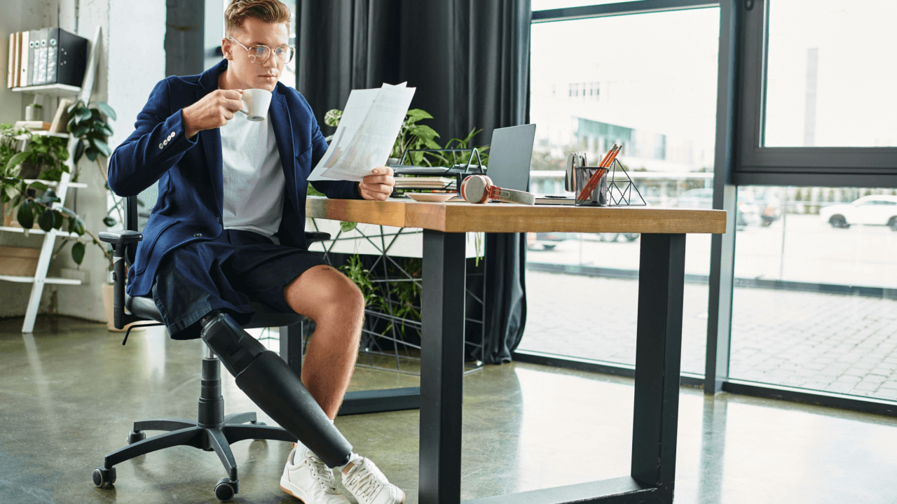 A man with a prosthetic leg sitting at a desk reviewing documents, representing someone researching is it hard to pass a continuing disability review