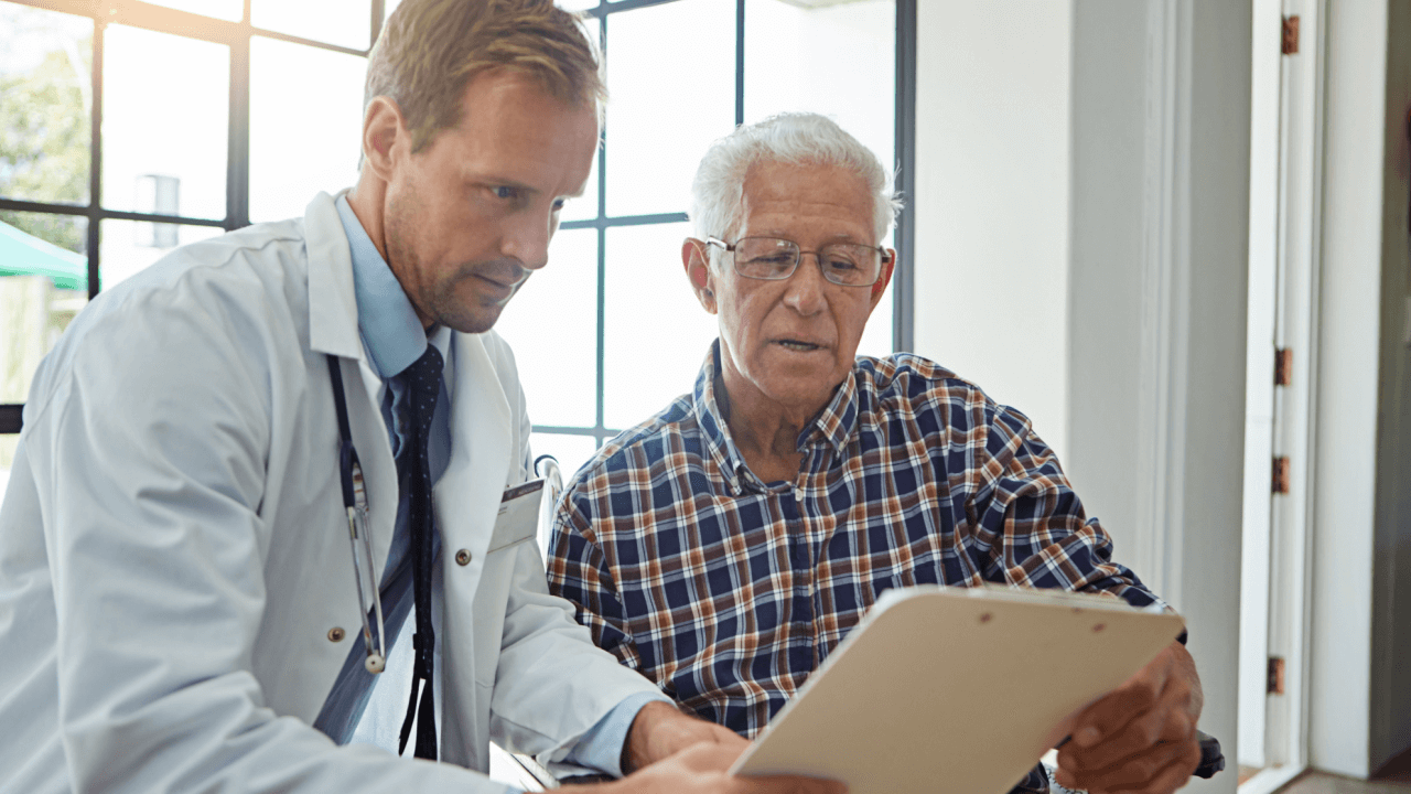 A doctor reviewing medical records with an elderly patient during a medical continuing disability review consultation