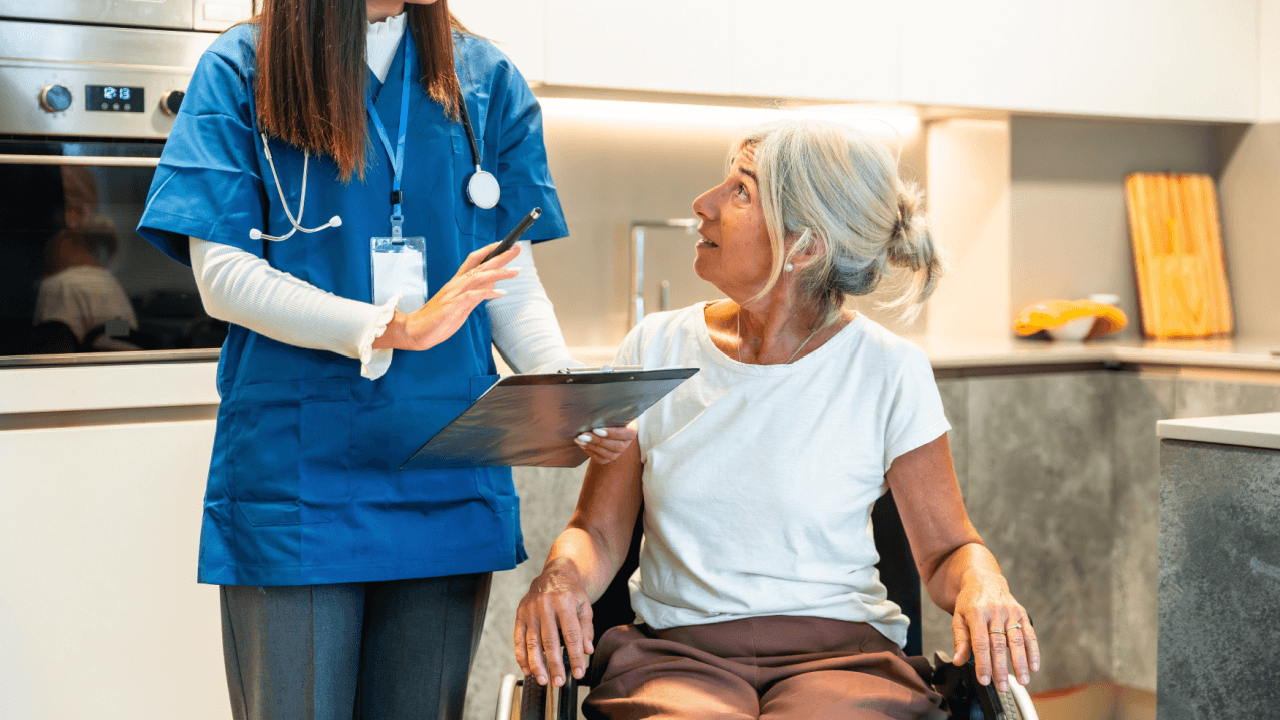 A healthcare professional explaining what triggers a CDR review to an elderly woman in a wheelchair during a home visit
