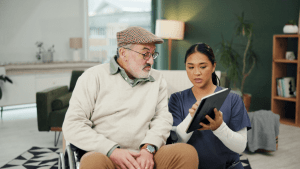A healthcare professional reviewing SSDI continuing disability review information on a tablet with an older adult in a wheelchair