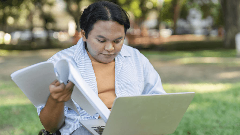 A person reviewing disability paperwork and laptop outdoors, researching why is my CDR taking so long