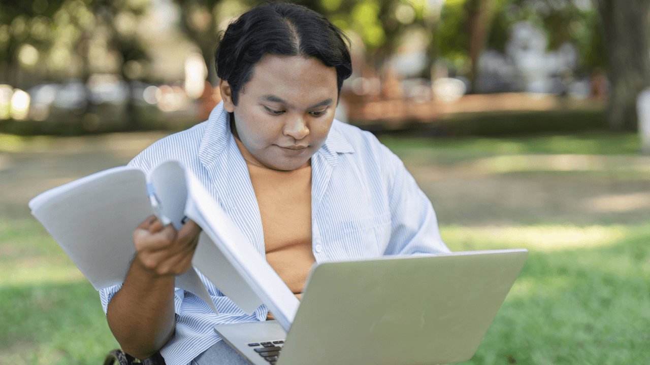 A person reviewing disability paperwork and laptop outdoors, researching why is my CDR taking so long
